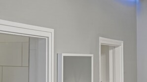 Um banheiro moderno com teto branco e faixa de luz LED azul ao longo da borda do teto.
