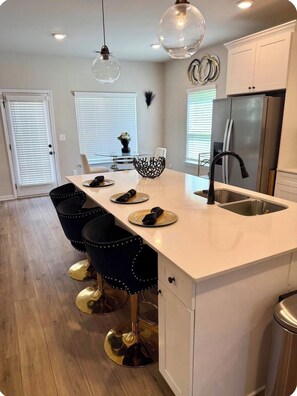 A modern kitchen with a central island, bar stools, a refrigerator, and pendant lighting. - Modern 4 bedrooms Luxury Home (Atlanta)
