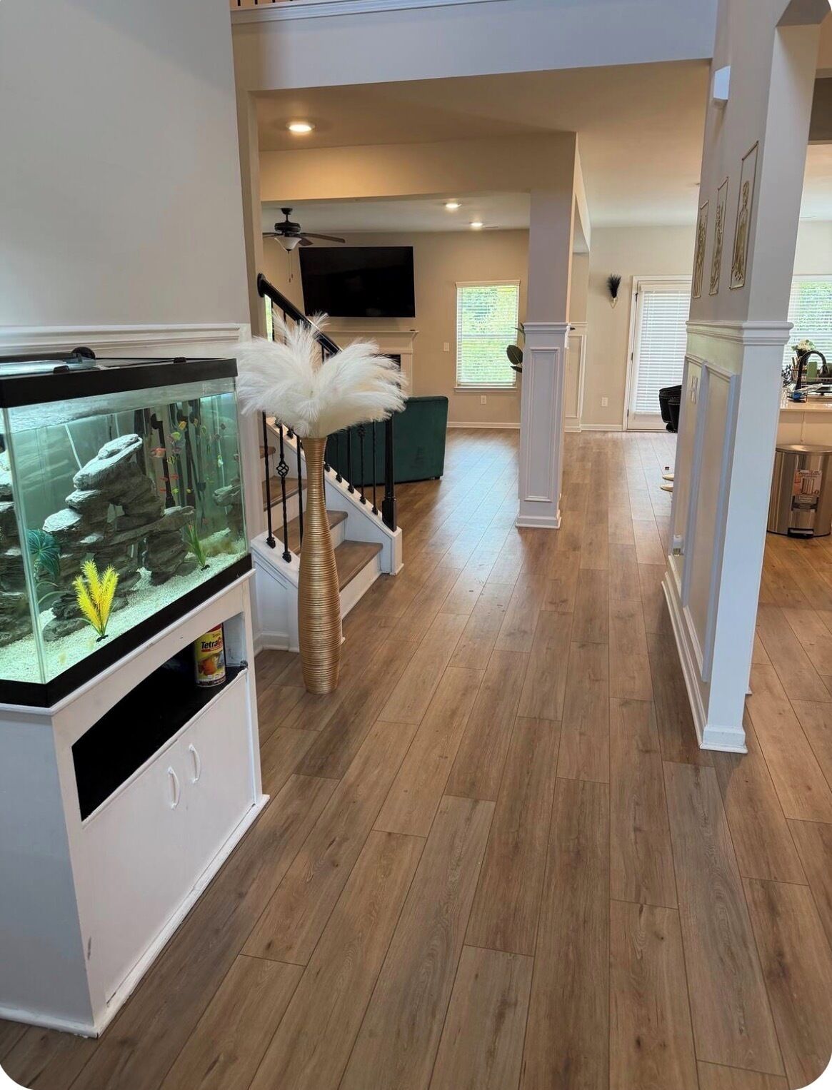 A spacious living area with a fish tank, staircase, and a television.