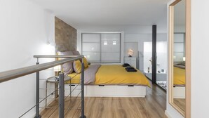 Une chambre moderne avec un lit, un bureau, une chaise et un grand miroir.