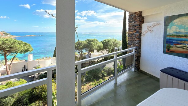 A balcony with a view of the sea, a stone wall, and a painting. - Exceptional Sea View – Terrace & Private Parking (ROSAS)
