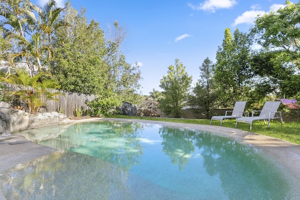 Private in-ground pool with easy-entry ramp surrounded by tropical gardens