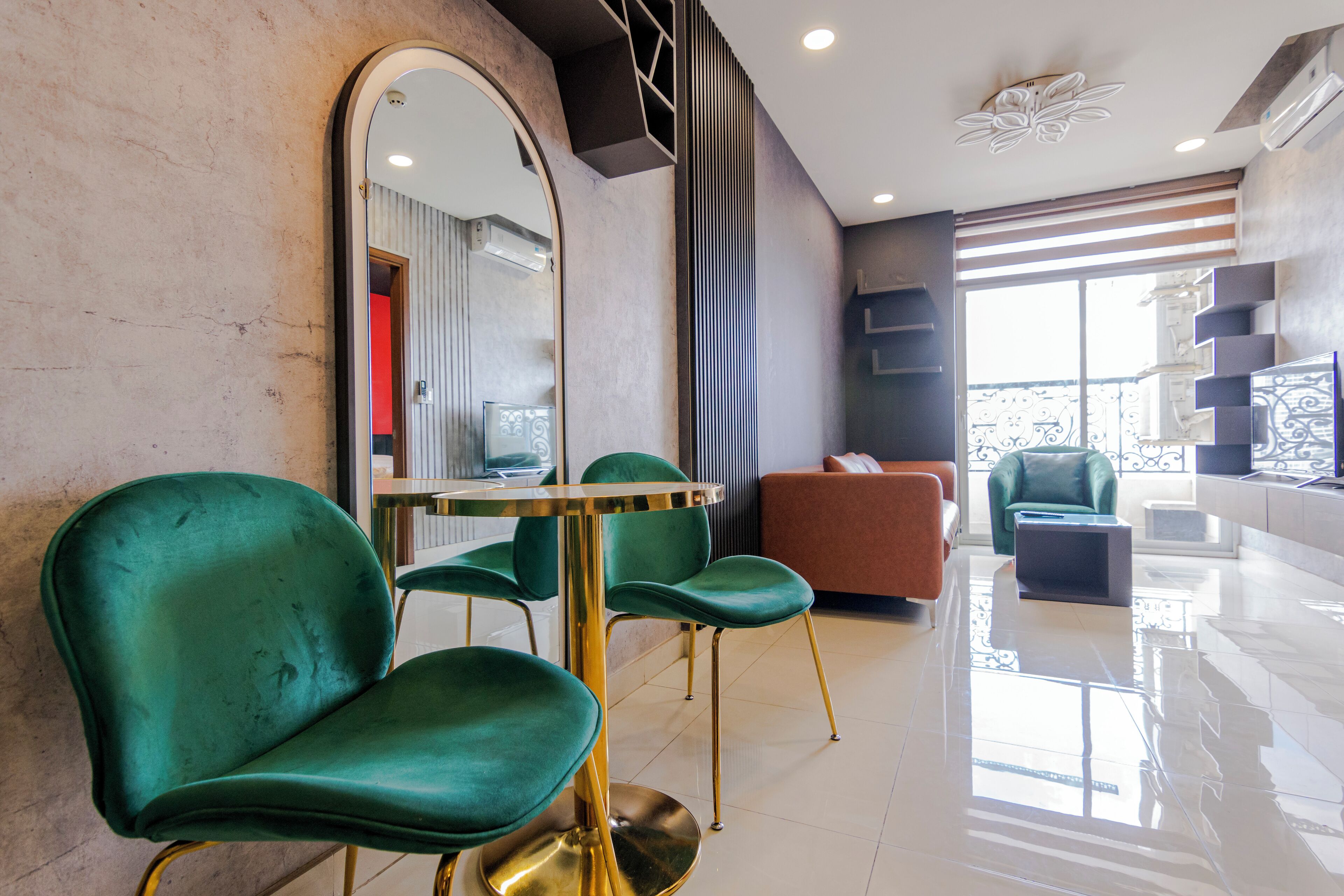 Un moderno vestíbulo de hotel con sillones tapizados en verde, una mesa redonda y un espejo grande.