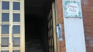 Ein Gebäudeeingang mit einer Holztür und einem Schild, auf dem 'Palazzina De Luca' steht.
