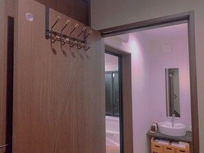 A wooden door with a coat rack, a bathroom with a sink and mirror, and a view of the outside. - touyouan momo house (Kyoto)