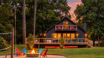 A cabin with a deck, outdoor seating, and a fire pit.