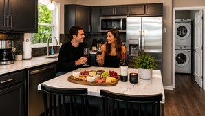 A modern kitchen with dark cabinets, stainless steel appliances, and a marble island with a cheese board. - Waterfront Renovated Modern A-Frame Hot Tub Game Room Kayaks (Shenandoah)