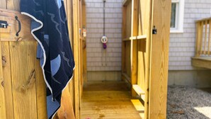 A wooden corridor leading to a room with a window, a towel hanging on the wall, and a basket with pink towels. - National Seashore/Updated/Game Room~Blue Pearl (Eastham)