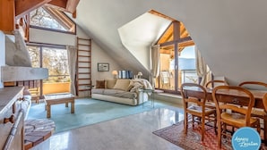 A cozy loft bedroom with a sloped ceiling, a wooden dining table, and a sofa. - Le Chapitre - Apartment T4 (Veyrier-du-Lac)