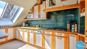 A kitchen with wooden cabinets, a gas stove, a microwave, and a skylight. - Le Chapitre - Apartment T4 (Veyrier-du-Lac)