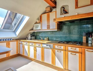 A kitchen with wooden cabinets, a gas stove, a microwave, and a skylight.