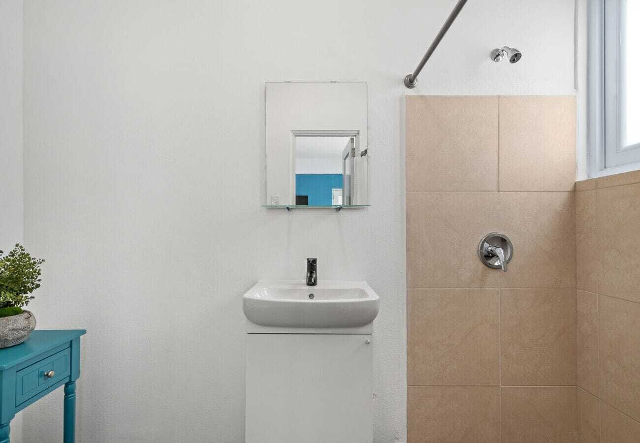 A bathroom with a white sink, a mirror, and a shower.