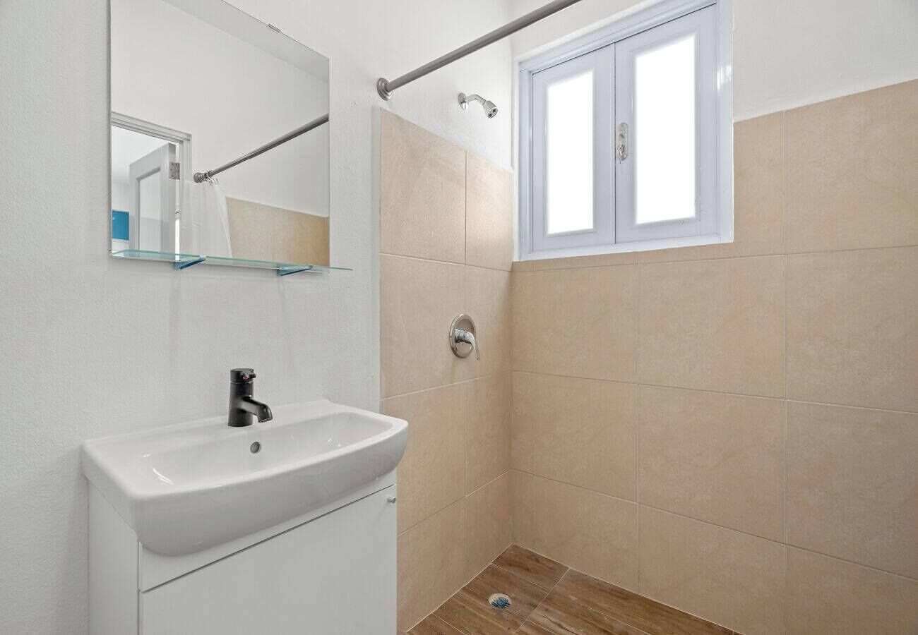 A bathroom with a white sink, a mirror, and a window.