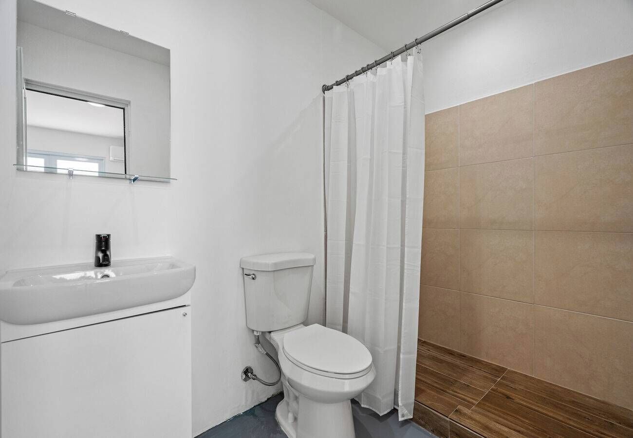 Et badeværelse med hvid vask, toilet og bruseforhæng.
