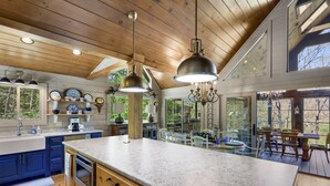 Una cocina amplia con armarios de madera, encimera de mármol e iluminación colgante.