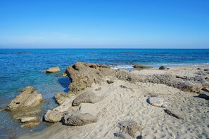 Uma costa rochosa com águas azul-claras e uma praia arenosa.
