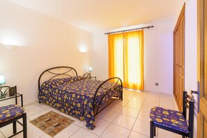 A bedroom with a bed, a chair, a nightstand, and a window with curtains. - 2-Bedroom Apartment 100m from the Beach - Private Terrace - Fiber Wi-Fi - A/C (Linguizzetta)