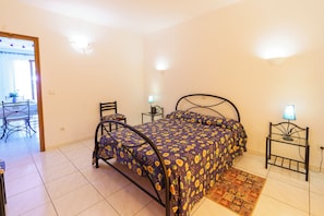 A bedroom with a bed, two bedside tables, a chair, a rug, and a window with curtains.