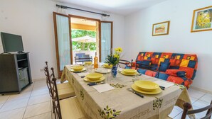 A dining area with a table set for four, a sofa, and a television in the corner.