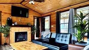 Un intérieur en bois avec une cheminée, un canapé en cuir et un téléviseur.