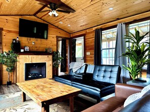 A wooden interior with a fireplace, leather sofa, and a television.