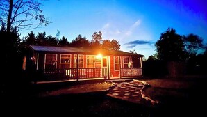 Une cabane en bois avec un porche, entourée d’arbres.