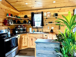Una cocina estilo cabaña de madera con electrodomésticos integrados, estantes de madera y un ventanal grande.