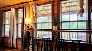 Un intérieur en bois avec un coin bar, de grandes fenêtres et une plante suspendue.