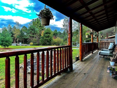 A wooden deck with a railing, potted plants, and a bench.. Mossy at Forest Villas: Private Axe Pit, Swing Fire Pit & Pergola Retreat