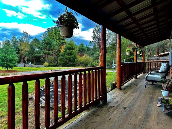 A wooden deck with a railing, potted plants, and a bench.