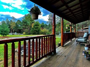 A wooden deck with a railing, potted plants, and a bench.