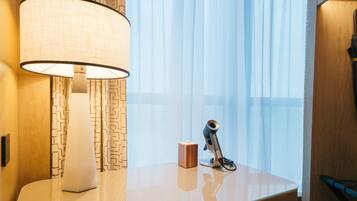 Een moderne hotelkamer met een bureau, een lamp, een camera en transparante gordijnen.