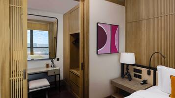 A hotel room with a bed, bedside table, lamp, and a large window.