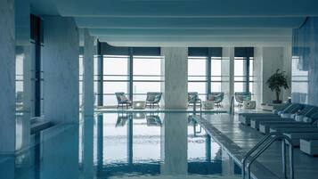 Una piscina techada, sillones reclinables de piscina