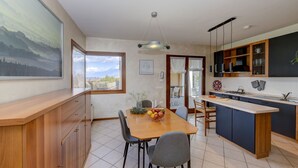 Una cocina moderna con una mesa de comedor de madera, sillas grises y un frutero.