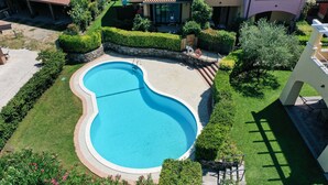 Una piscina rodeada de césped y setos bien cuidados.