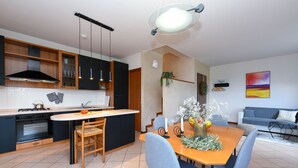 Una cocina moderna con una isla central, armarios negros y un comedor con sillas azules.