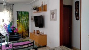 A living room with a TV, a wooden cabinet, a glass table, and a door. - Cozy villa with large private pool and complete barbecue (El Mirador del Penedès)