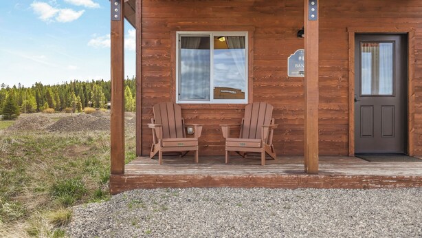 A wooden cabin with two Adirondack chairs outside, a door, and a window with a sign. - Family-Friendly Old West Cabin Near YNP (Island Park)