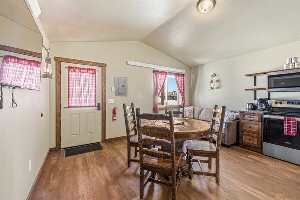 A cozy kitchen with a wooden dining table, chairs, and a built-in oven.