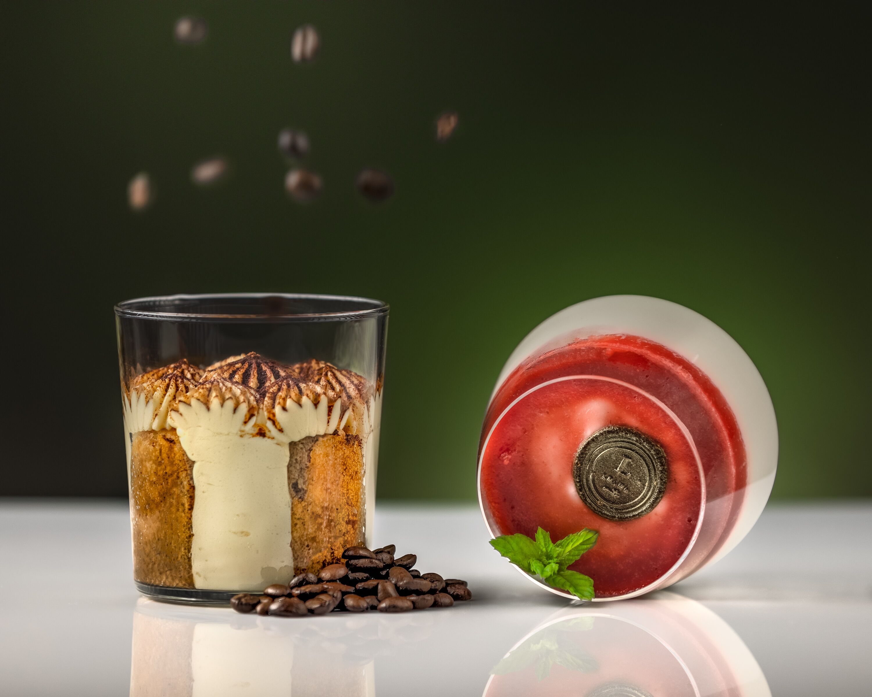 Un vaso de postre en capas con granos de café y hojas de menta a un lado.