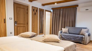 A bedroom with two beds, a sofa, wooden doors, and a window with curtains. - Guest House Pri Cesarju (Kamnik)