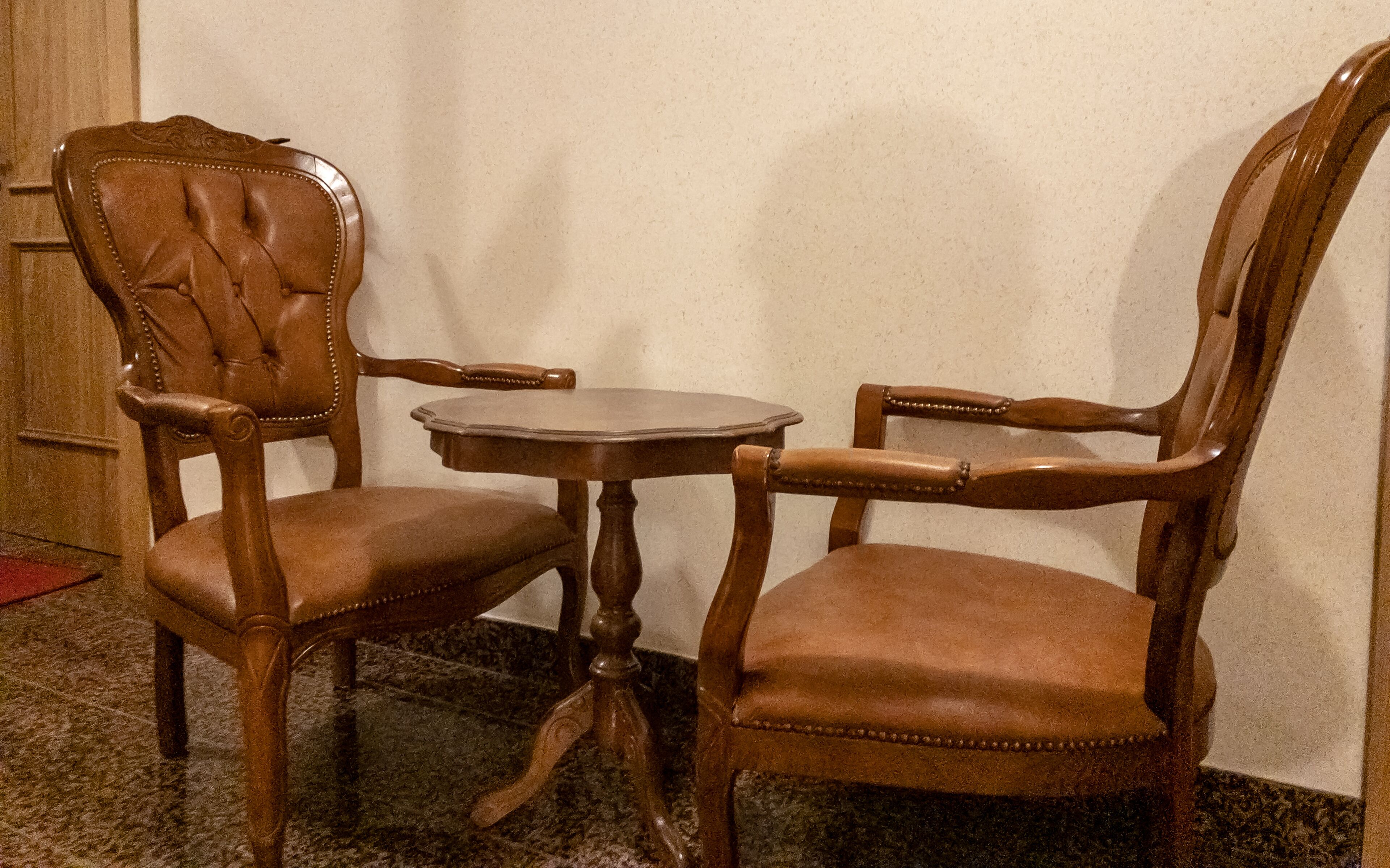 Eine Sitzecke mit zwei Holzstühlen und einem kleinen runden Tisch.