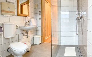 Un baño moderno con inodoro, lavamanos y ducha.