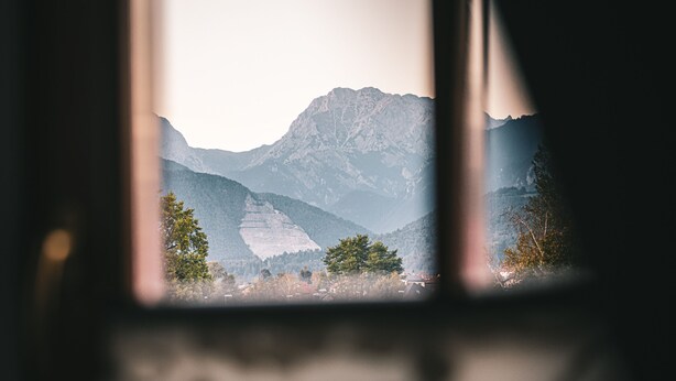 A mountain landscape through a window with a visible mountain peak and trees. - Guest House Pri Cesarju (Kamnik)