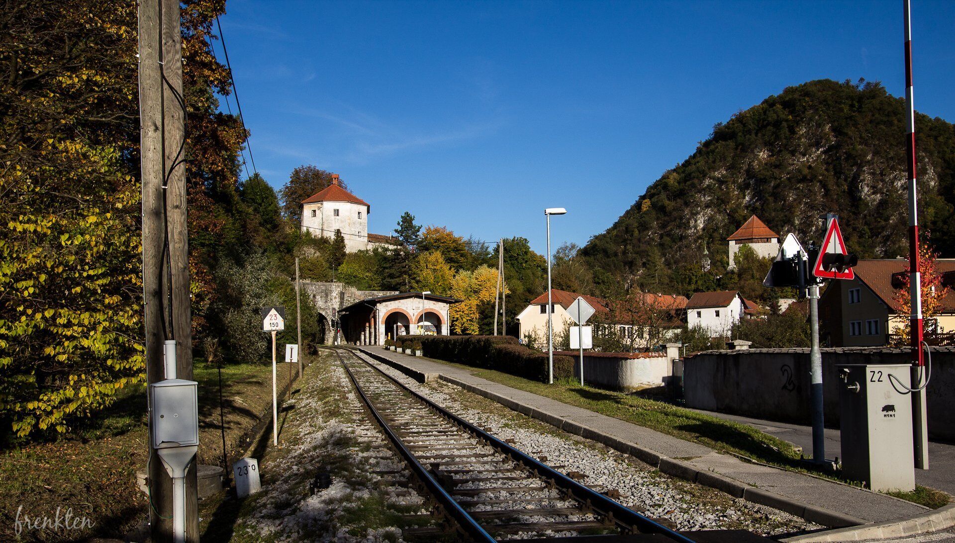 A railway track with a small station building, a tower, and a mountain in the background.