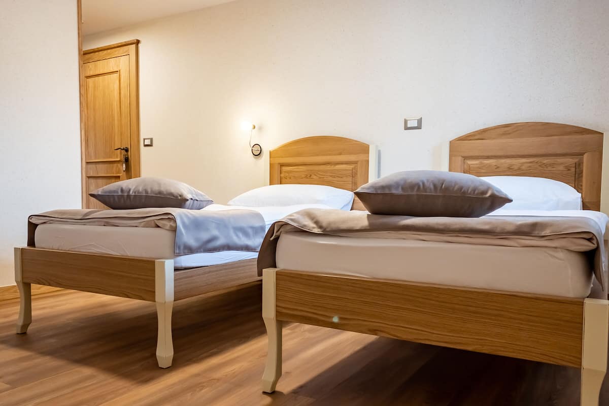 A room with two wooden beds, each with a headboard, and a wooden door.