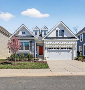 A two-story house with a garage, a red door, and a small front yard with a tree. - Arbor-Lyn * 4BR Luxury House, Sleeps 10 (Rehoboth Beach)