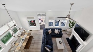A modern living room with a sectional sofa, a dining table, and a fireplace. - Arbor-Lyn * 4BR Luxury House, Sleeps 10 (Rehoboth Beach)