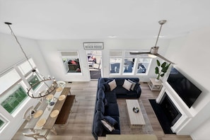 A modern living room with a sectional sofa, a dining table, and a fireplace.